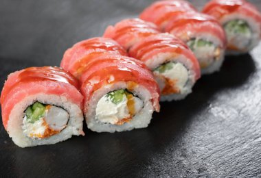 Karides kaplanlı uramaki suşi rulosu, havyar, siyah arka planda ton balığıyla kaplı unagi. Suşi menüsü. Japon mutfağı, restoran..