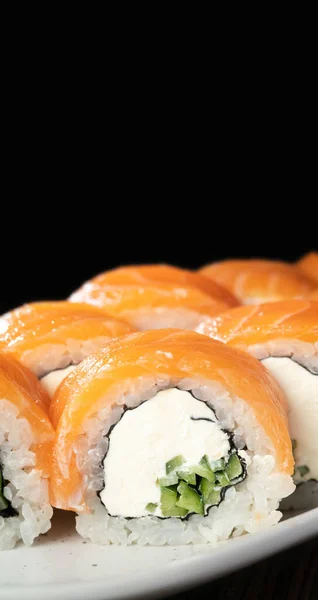 Sushi Philadelphia with salmon, avocado and cheese on black background. Traditional sushi. Japanese cuisine. Vertical banner