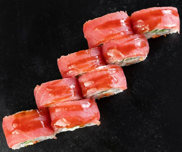 Sushi roll with tuna, tiger shrimp, cucumber, cream cheese on a black background. Sushi menu concept. Japanese food.