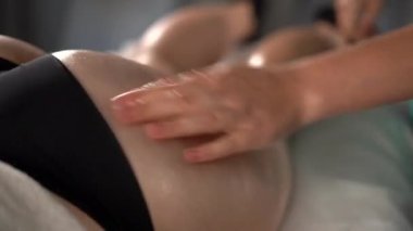 Anti selülit tedavisi. Masör spa salonundaki genç bayana antielülit masajı yapıyor. İyileştirme Masajı ve Vücut Bakımı