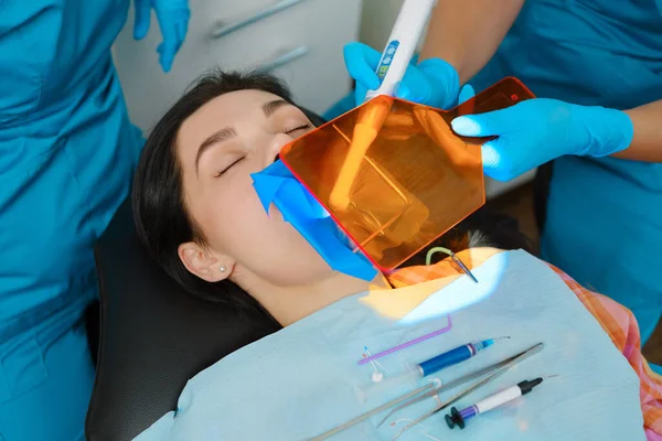 Dentist uses photopolymer lamp to cure carious teeth of the patient