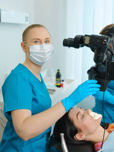 Female Dentist Using Dental Microscope Treating Patient Teeth Dental Clinic — стоковое фото