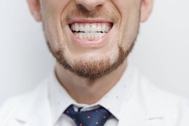 Closeup shot of male mouth with clear aligners or invisible braces on his teeth treatment