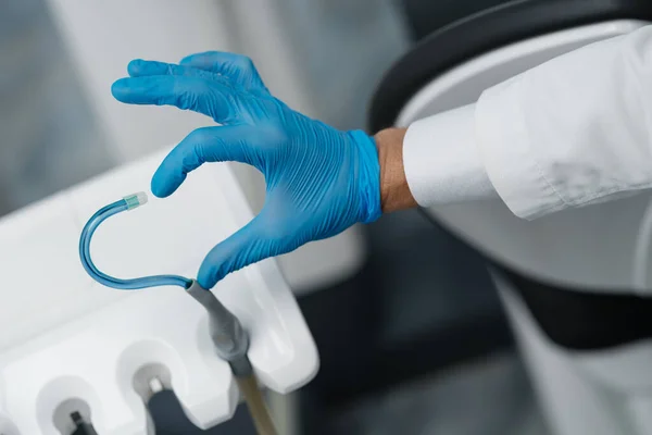 Saliva ejector and a hand in a disposable glove symbolize love in dentistry. Hand in a blue glove with blue saliva ejector. Heart symbol.