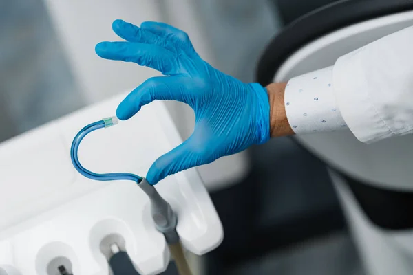 Saliva ejector and a hand in a disposable glove symbolize love in dentistry. Hand in a blue glove with blue saliva ejector. Heart symbol.