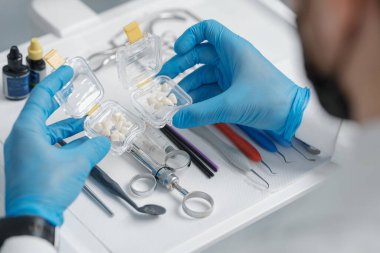 Transparent transportation box with veneers made of pressed ceramics in hands of orthodontist in a dental office. Holywood smile concept