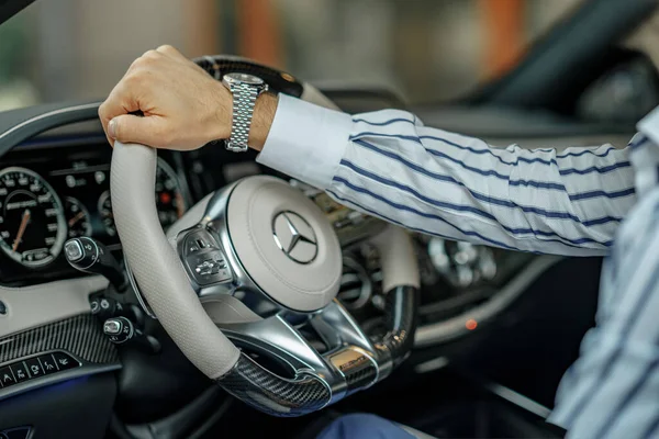 Kyiv, Ukraine - July 23, 2021: Steering wheel of a luxurious Mercedes-Benz AMG vehicle with male hand on top of it