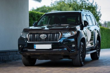 Kyiv, Ukraine - August 23th 2022: Toyota Land Cruiser Prado in black color parked near house on a sunny day. Modern SUV from Japanese manufacturer