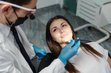 Over the shoulder view of a dental doctor treating female patient. Female having routine dental checkup at dentist.