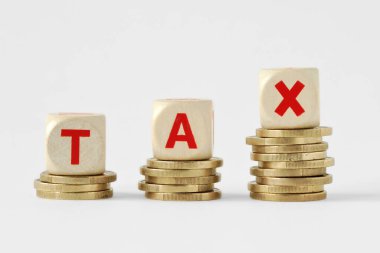 Vergi sözcüğü bozuk paraların tepesinde tahta bloklar ile yazıldı - Vergi artırma kavramı