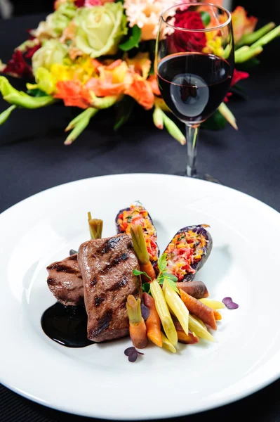 Bifteck d'oeufs juteux dans une assiette et un verre de vin rouge — Photo