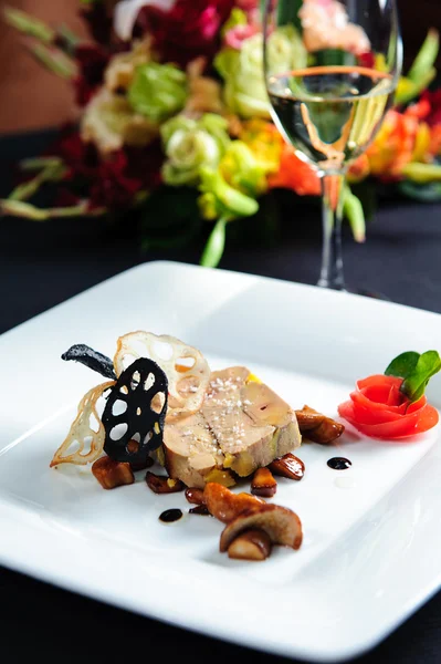 Juicy goose liver on a plate and glass of white wine — Stock Photo, Image