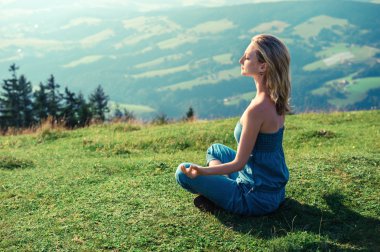 Genç bir kadın dışarıda meditasyon yapıyor.
