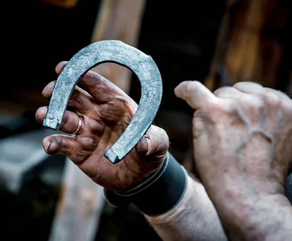 Las manos sucias del herrero sosteniendo herradura — Foto de Stock