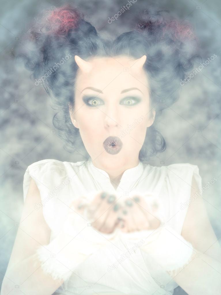 Portrait of devil woman blowing a white powder