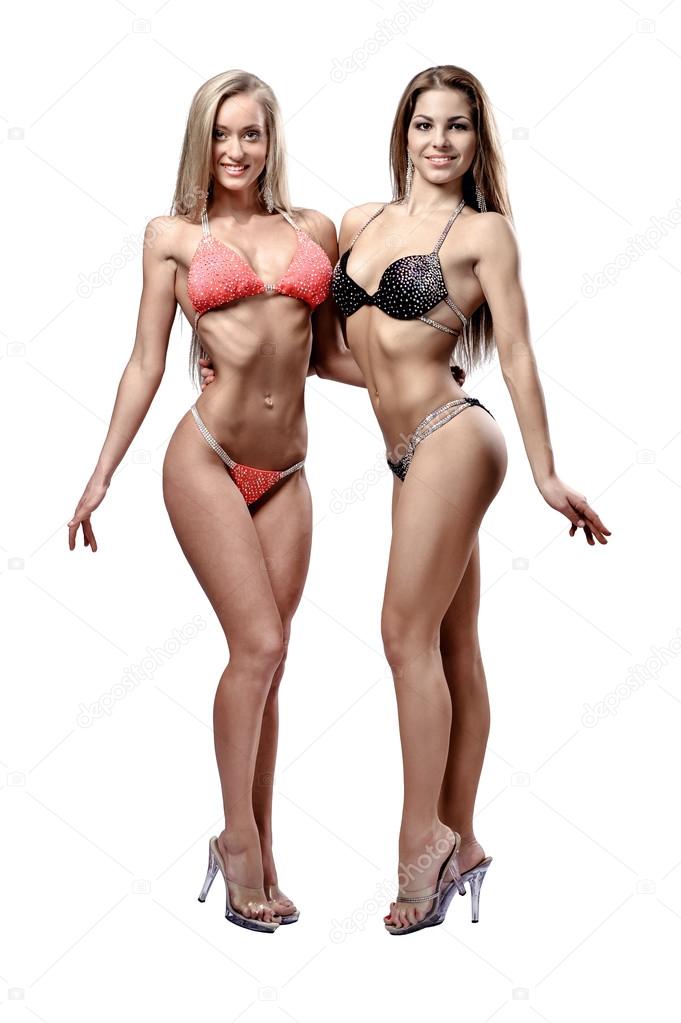 Two beautiful athletic girl wearing bikini posing indoors