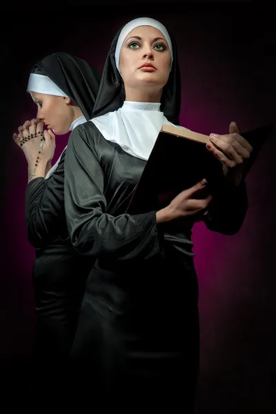 Dos atractivas monjas jóvenes con cuentas y la Biblia rezando — Foto de Stock