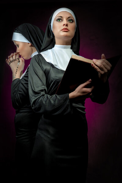 Two attractive young nuns with beads and bible praying