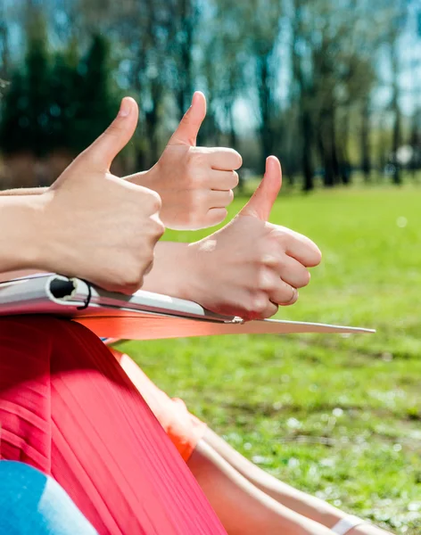 Students with thumbs up outdoors — Stock Photo, Image