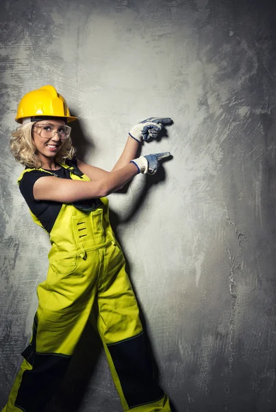 Mujer constructora atractiva mostrando algo con las manos —  Fotos de Stock