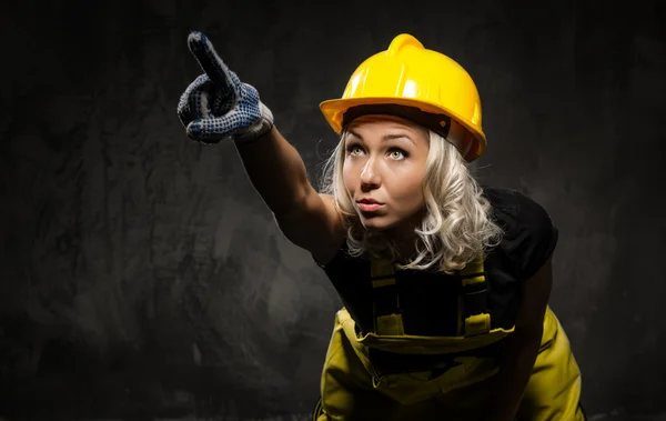 Mujer constructora atractiva mostrando algo con la mano —  Fotos de Stock