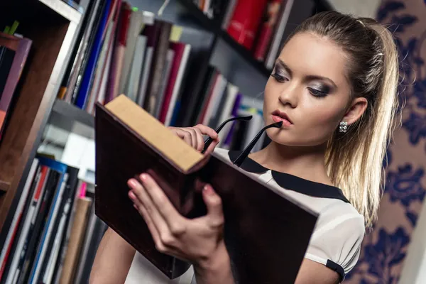 Étudiante à la bibliothèque tenant un livre — Photo