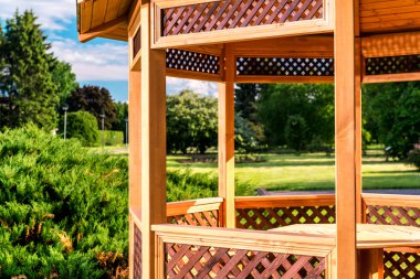 Outdoor wooden gazebo over summer landscape background clipart