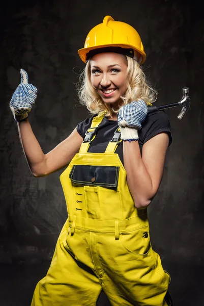 Attractive smiling builder woman with hammer showing thumbs up — Stock Photo, Image