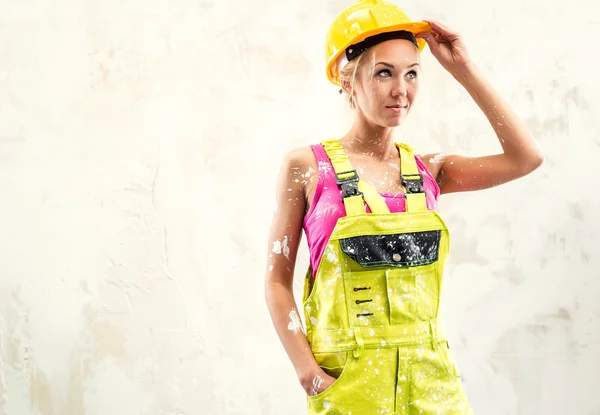 Trabalhadora da construção feminina posando sobre parede branca obsoleta — Fotografia de Stock