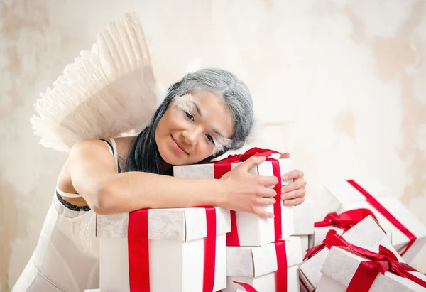 Junge Frau als Engel mit Haufen von Geschenkboxen — Stockfoto
