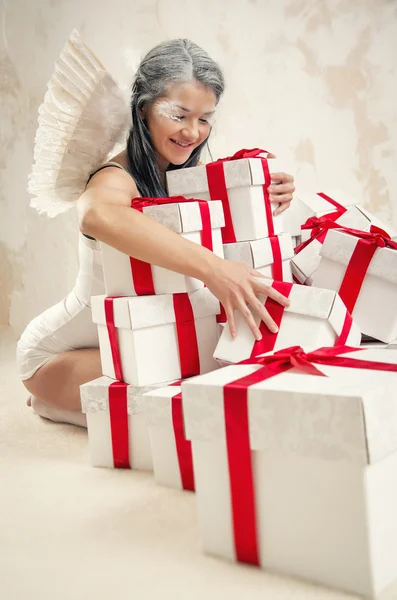 Schöne junge Frau als Engel mit Haufen von Geschenkboxen — Stockfoto