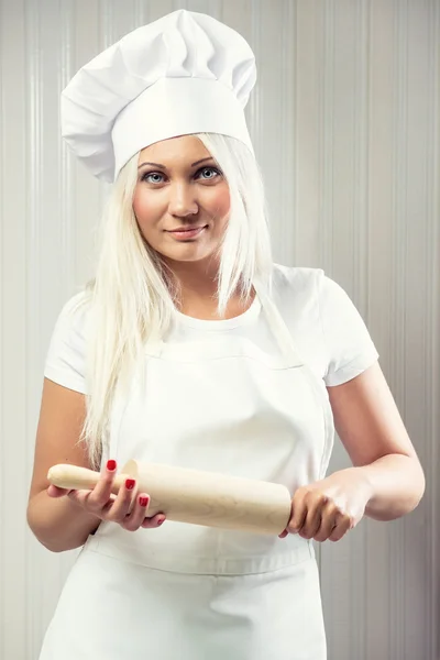 Femme tenant rouleau à pâtisserie portant uniforme posant à l'intérieur — Photo