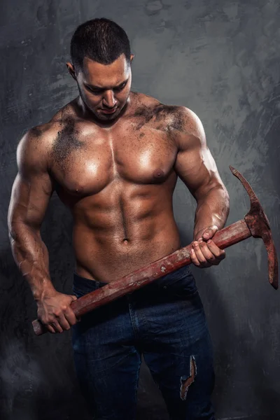 Muscular man holding pickaxe — Stock Photo, Image