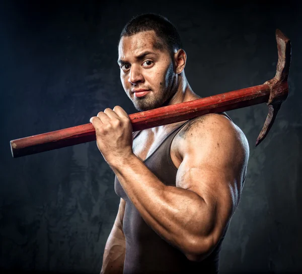 Muscular man holding pickaxe — Stock Photo, Image