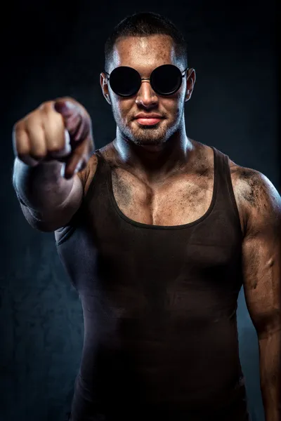 Muscolare bello giovane uomo in occhiali da sole che punta su di voi — Foto Stock