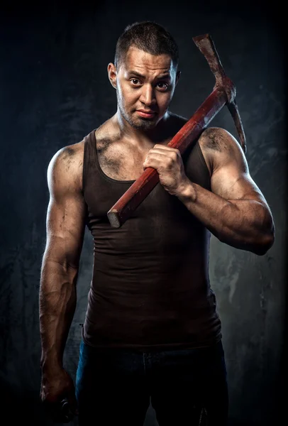 Muscular man holding pickaxe — Stock Photo, Image