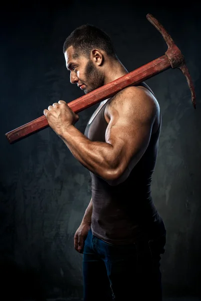 Muscular man holding pickaxe — Stock Photo, Image