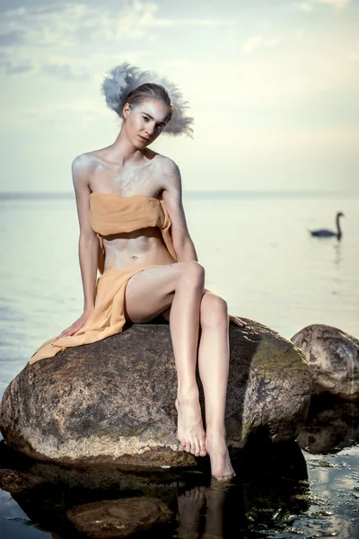 Jonge mooie vrouw als zwaan die zich voordeed op het strand — Stockfoto