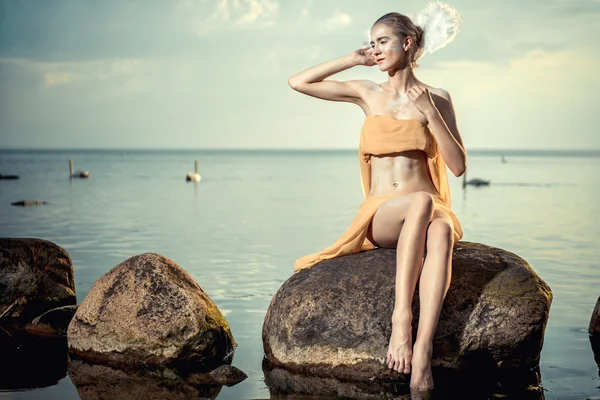 Mladá krásná žena jako Labutí pózuje na pláži — Stock fotografie
