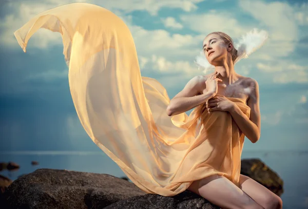 Jonge mooie vrouw als zwaan poseren op het strand bij zonsondergang — Stockfoto