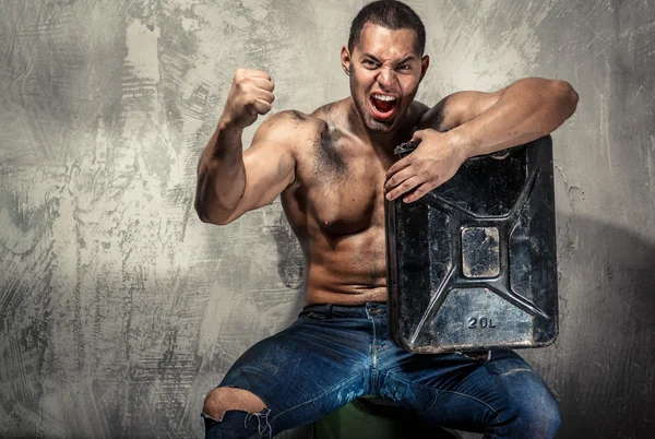 Muscular man with metal fuel can indoors — Stock Photo, Image