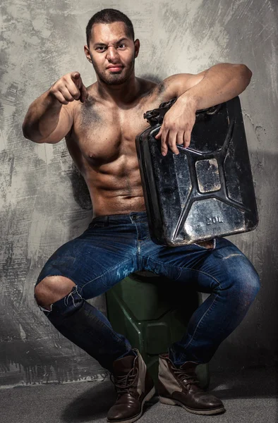 Uomo muscolare con carburante in metallo può al chiuso — Foto Stock