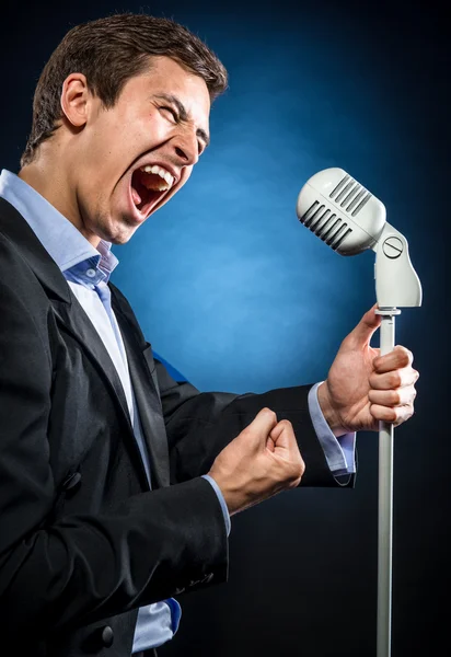 Homem de casaco preto elegante e camisa azul cantando — Fotografia de Stock