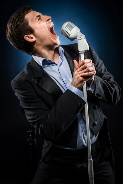 Homem de casaco preto elegante e camisa azul cantando — Fotografia de Stock