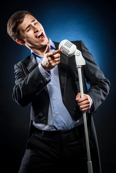Man in elegante zwarte jas en blauw shirt zingen — Stockfoto