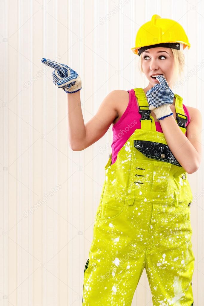 Woman wearing coverall and hard hat posing indoors