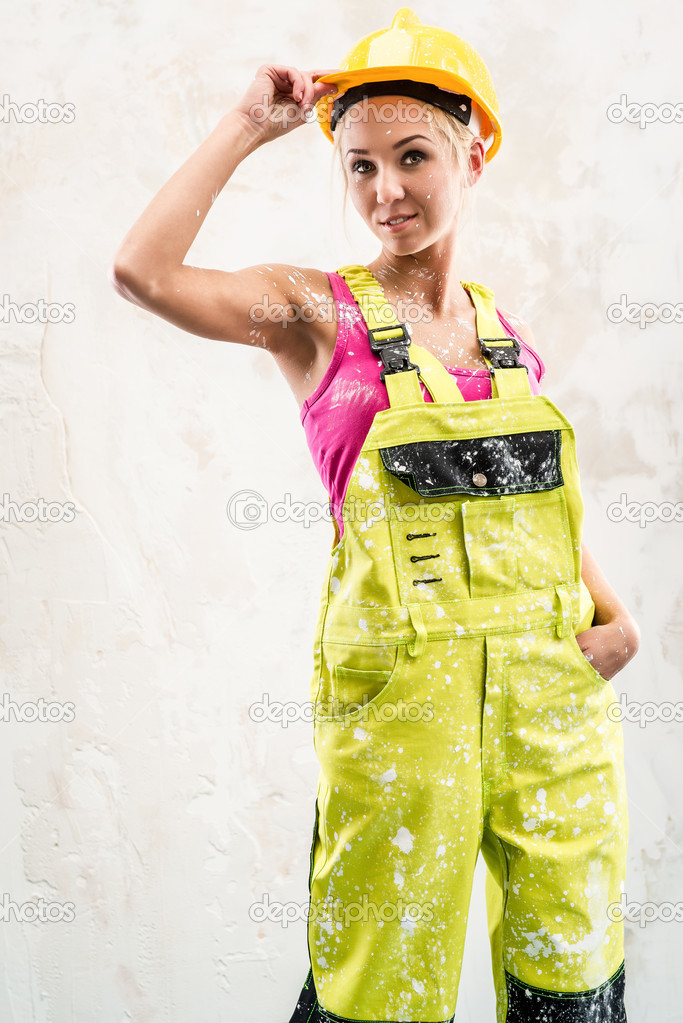 Female construction worker posing over white obsolete wall