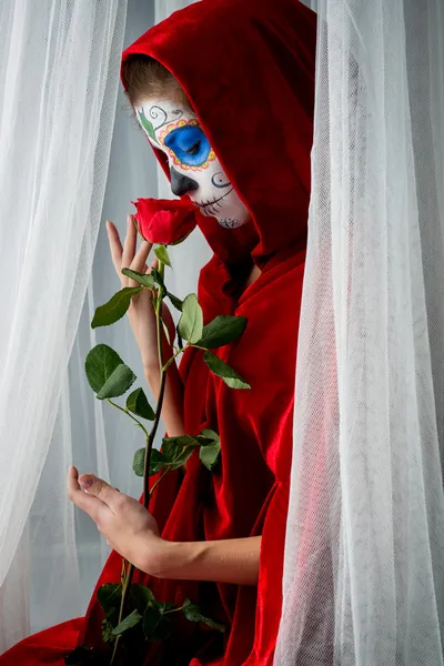 Day of the dead girl with sugar skull makeup holding red rose — Stock Photo, Image