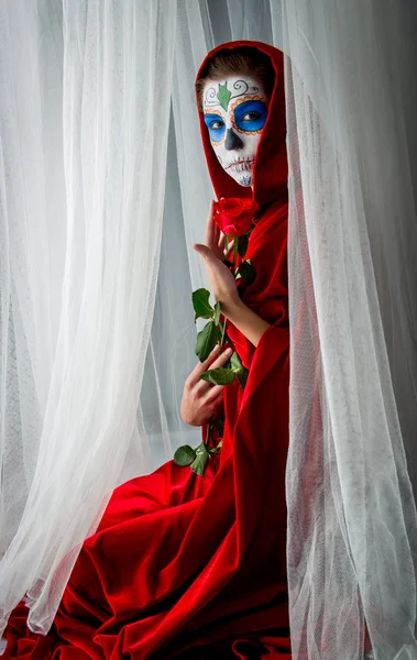 Day of the dead girl with sugar skull makeup holding red rose — Stock Photo, Image