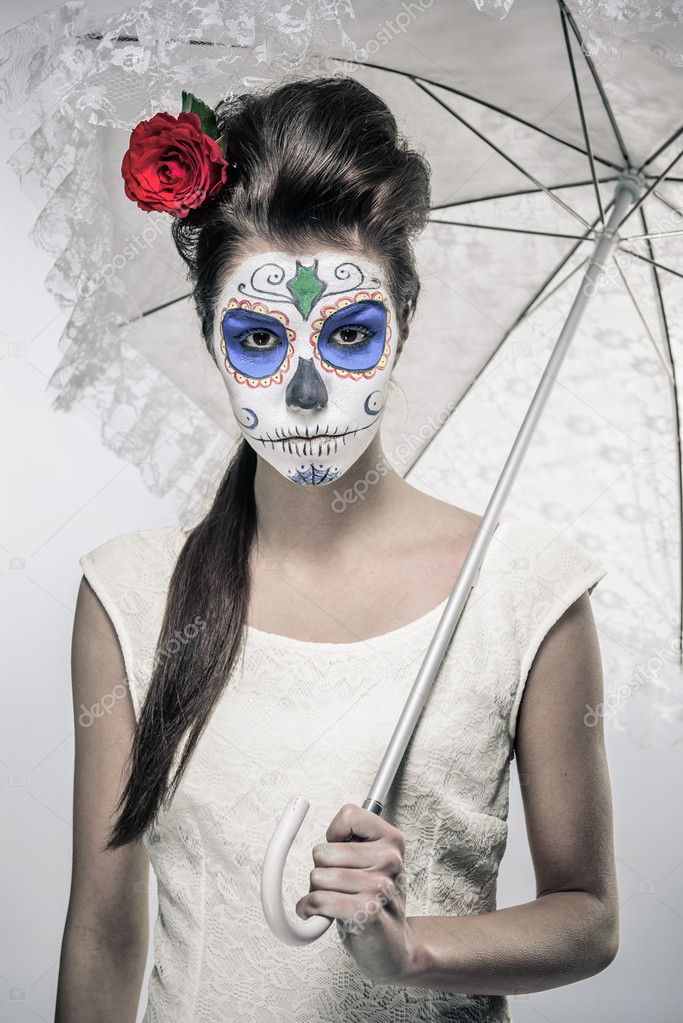 Day of the dead girl with sugar skull makeup holding lace umbrel